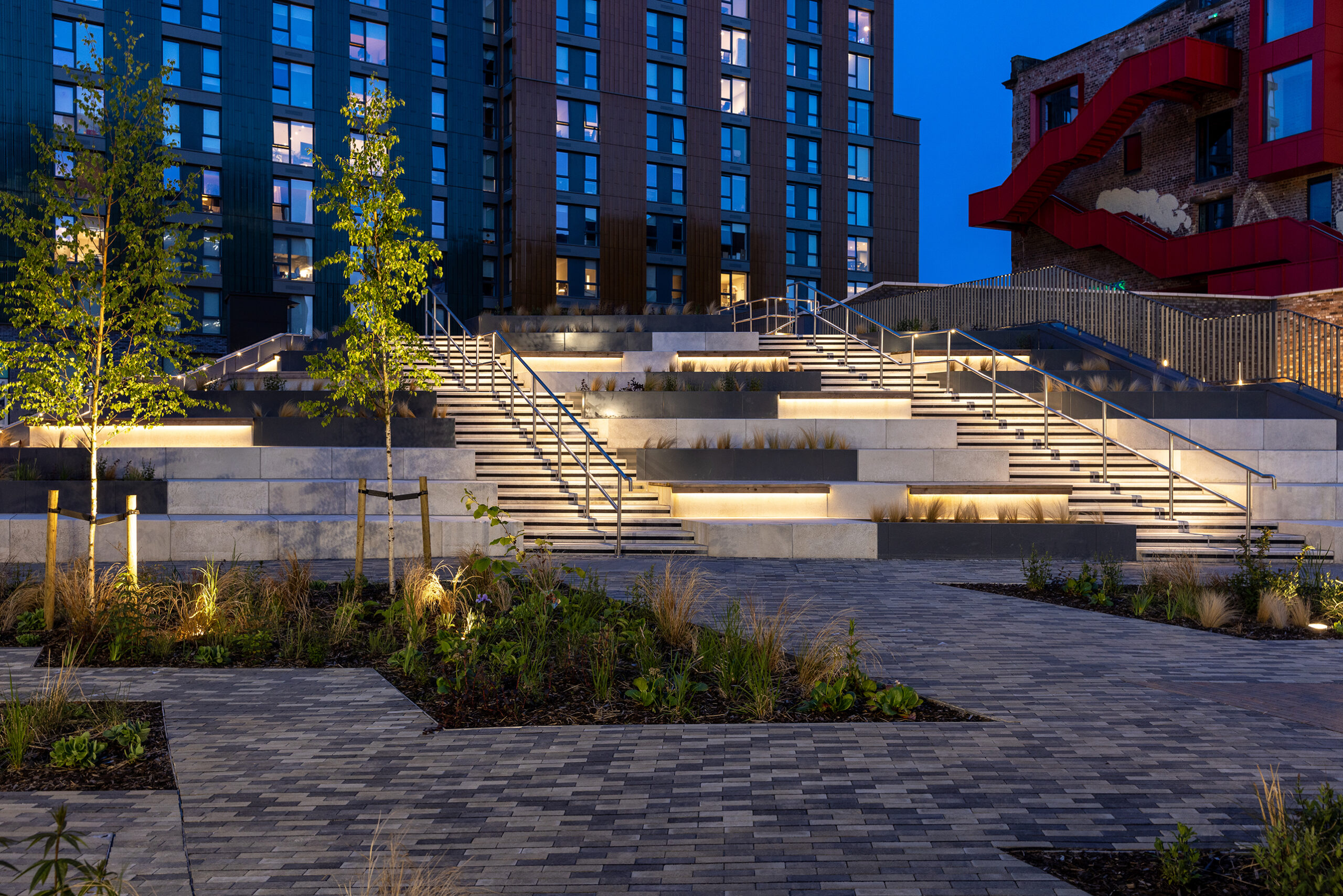 Beco Barclays Dragonfly campus, view of the tiered stairs at night time with lights leading up to main high-rise building